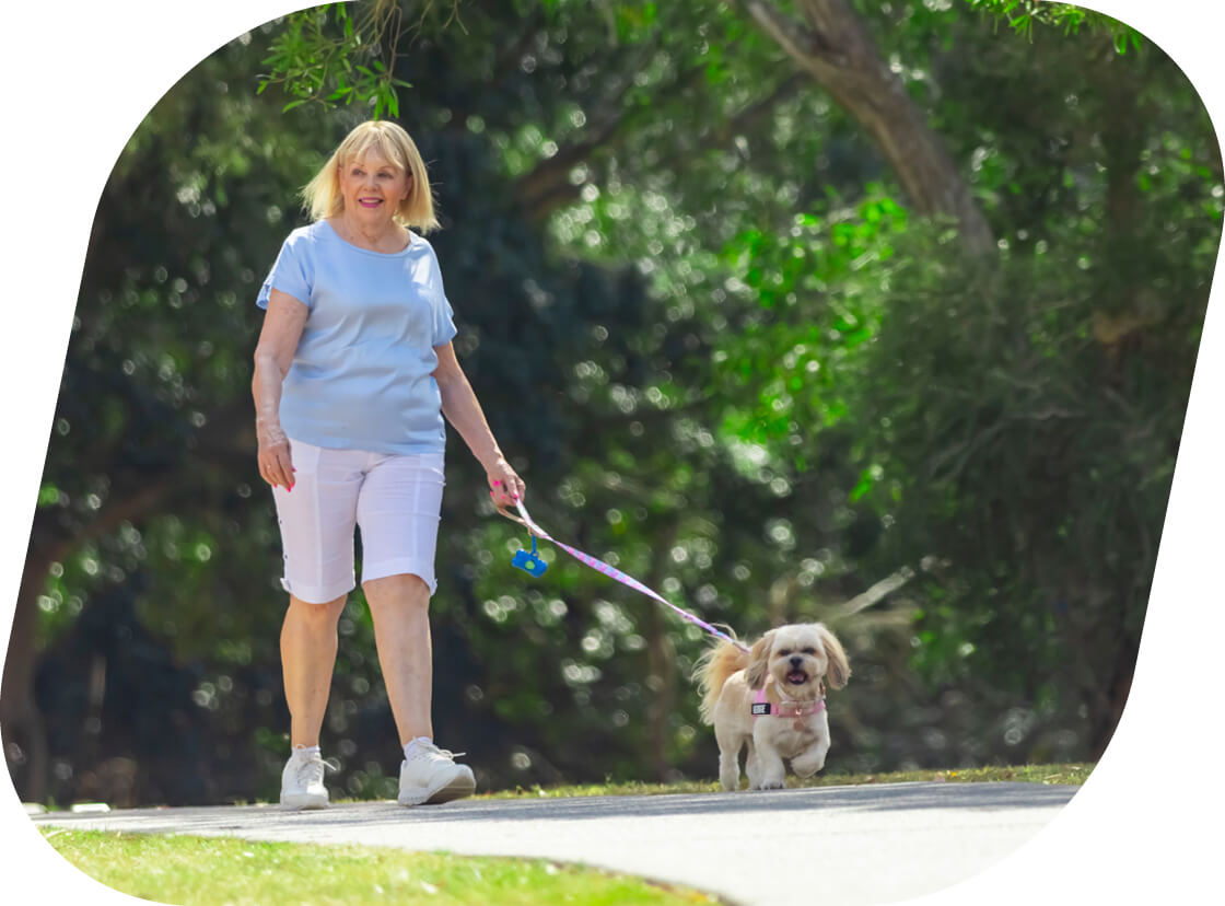 Older woman walking her dog along a path
